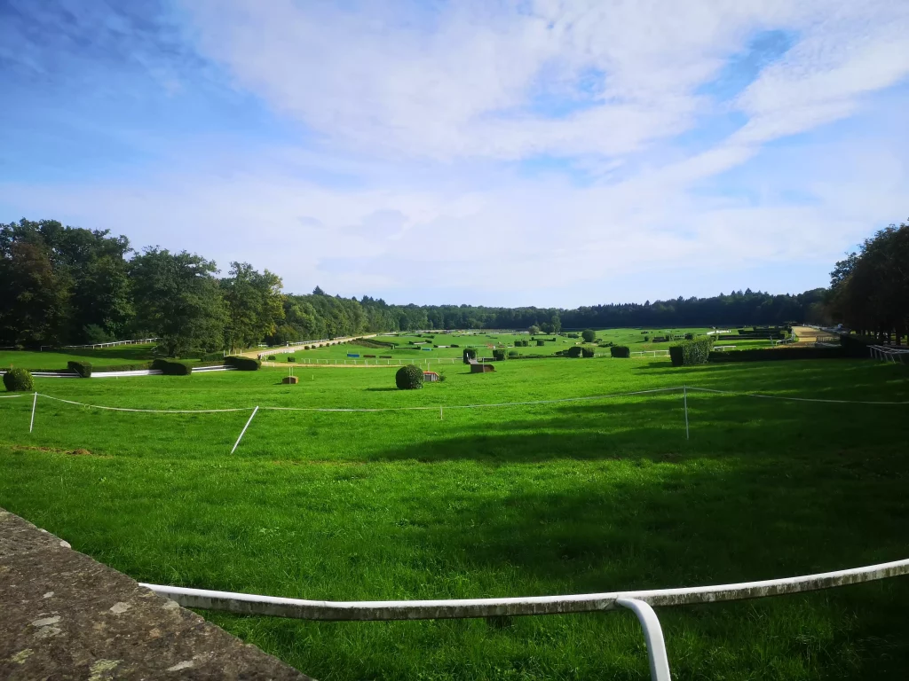 Une vue de l’hippodrome, vaste pelouse, obstacles et ciel bleu.